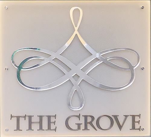 Our logo, a modern chrome chandelier, recreated in a shiny, mirror-finish as a backlit sign on the middle panel of our Reception Desk