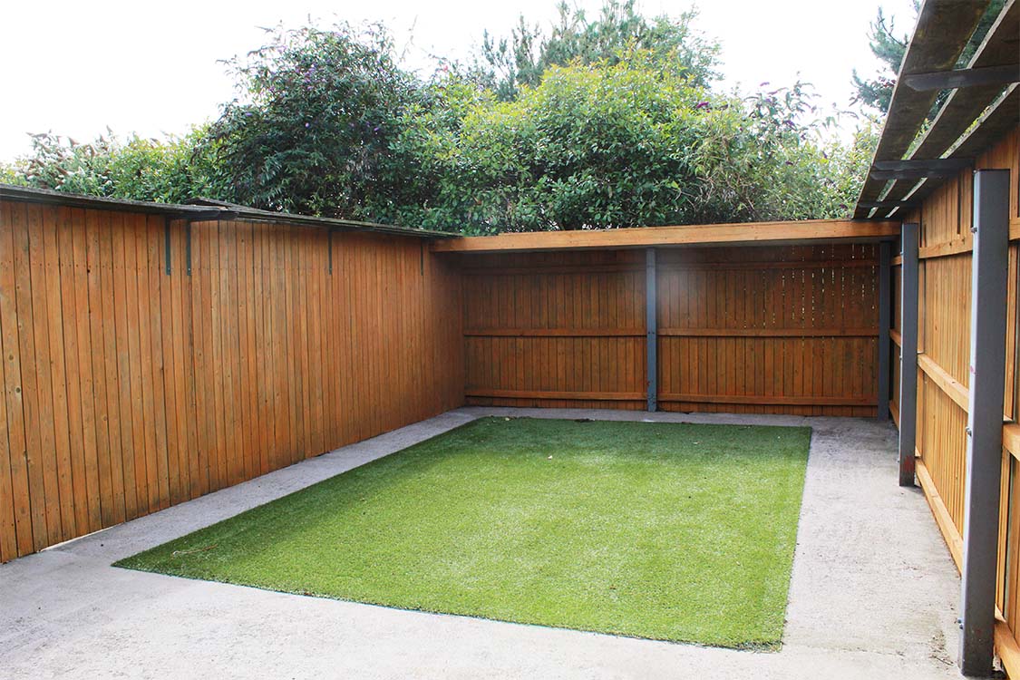 Small garden with a central grass area, surrounded by a pathway and timber fencing