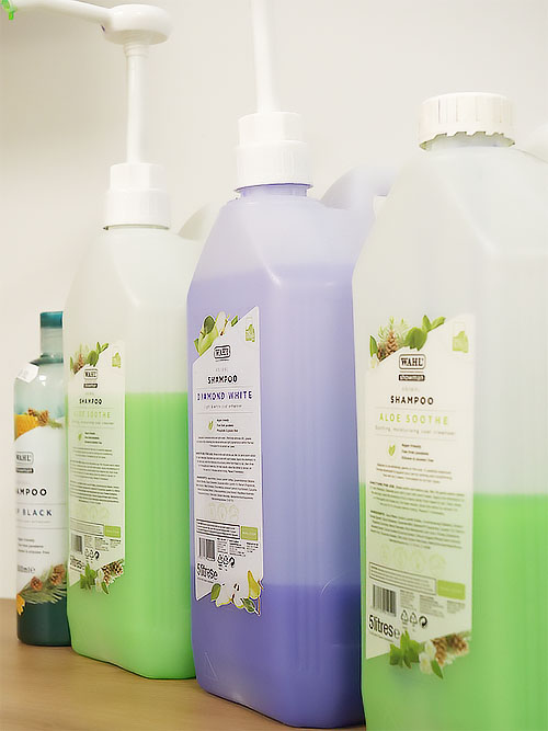 Three large opaque shampoo bottles, two bottles have lime green coloured shampoo and one bottle has lavender coloured conditioner